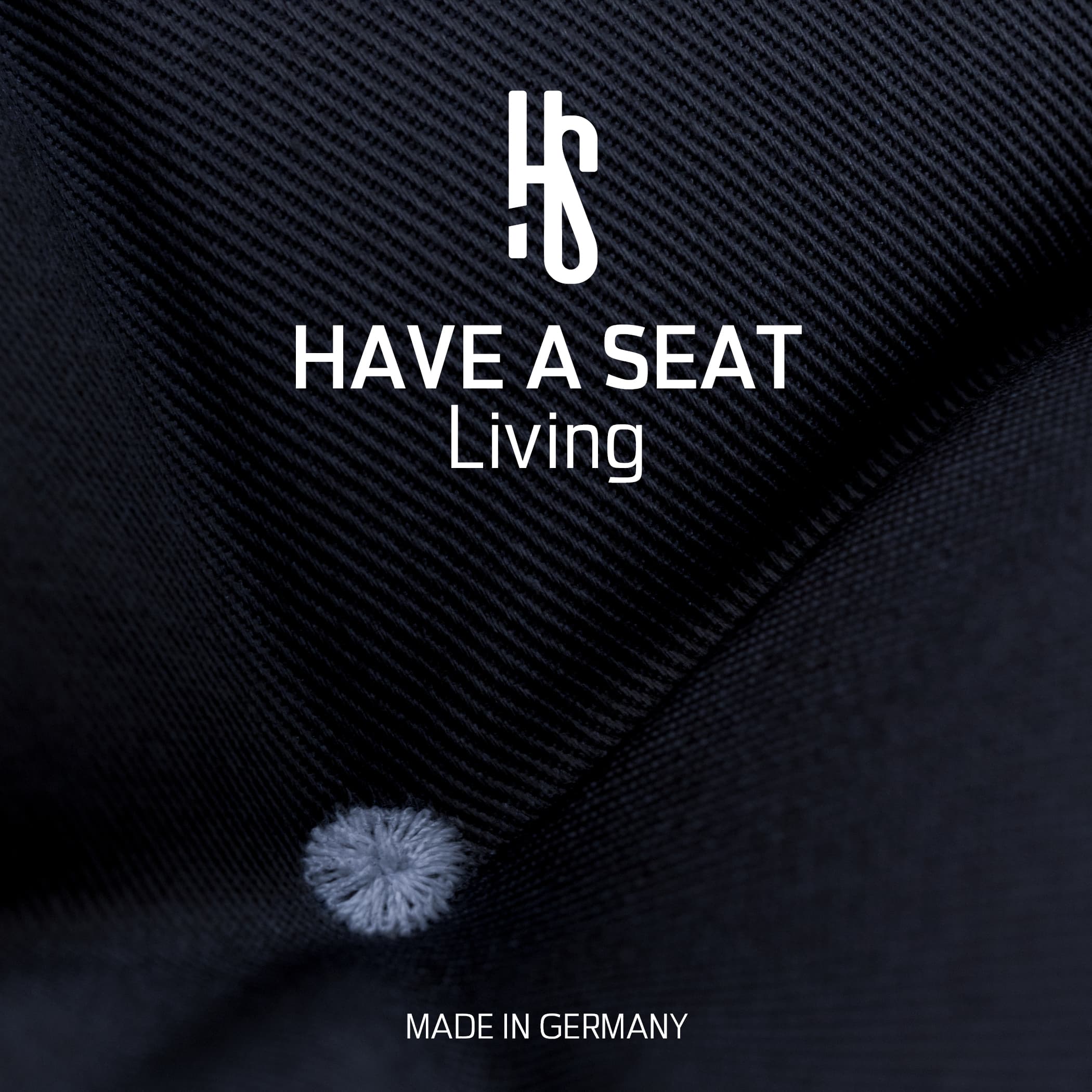 Nahaufnahme des Blauen Stoffbezugs mit Markenlogo „Have A Seat Living“ und Hinweis „Made in Germany“.